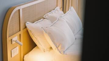 A bedroom with a bed, a bedside table, a nightstand, and a wall-mounted light switch.