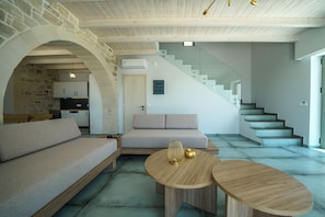 A modern living room with a sofa, coffee table, and staircase. - Luxury Villa Odysseus Nafsika Xenia Falassarna
sea view sunset,modern, privacy (Phalasarna)