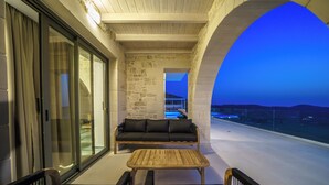 Un balcon aménagé avec un canapé, des fauteuils et une table, d’où l’on peut admirer une piscine et un paysage montagneux.