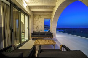 A balcony with a sofa, chairs, and a table, overlooking a pool and a mountainous landscape. - Luxury Villa Odysseus Nafsika Xenia Falassarna
sea view sunset,modern, privacy (Phalasarna)