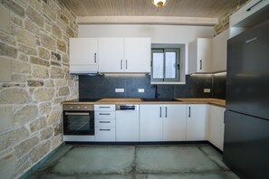 A kitchen with white cabinets, a built-in oven, a dishwasher, and a refrigerator. - Luxury Villa Odysseus Nafsika Xenia Falassarna
sea view sunset,modern, privacy (Phalasarna)