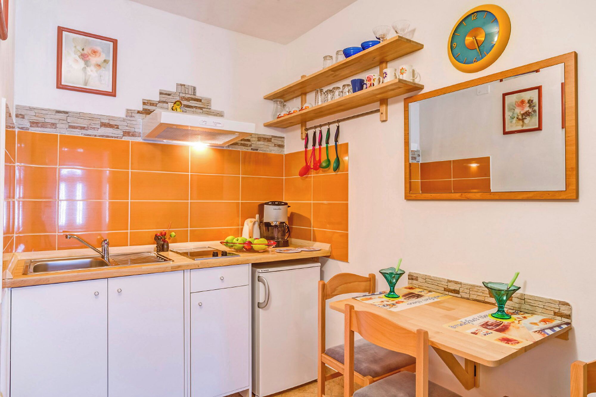 A compact kitchen with a sink, stove, and a dining area with a table and chairs.