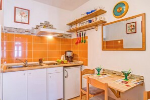 Eine kompakte Küche mit Spüle, Herd und einem Essbereich mit Tisch und Stühlen.