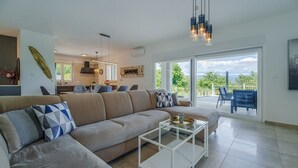 Uma sala de estar moderna com sofá, mesa de centro e vista para o exterior.