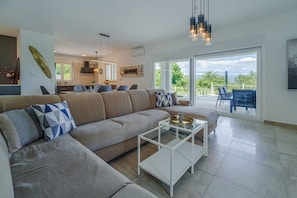 Ein modernes Wohnzimmer mit Sofa, Couchtisch und Blick ins Freie.