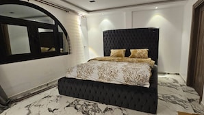 Ein Schlafzimmer mit einem großen Bett, einem dunklen Kopfteil und einem Marmorboden.