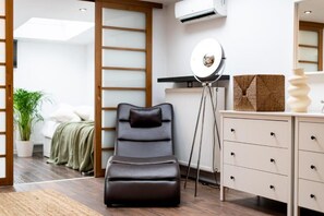 A modern room with a massage chair, a standing lamp, a dresser, and a radiator. - Malila Premium Apartments Cracow Grodzka (Kraków)