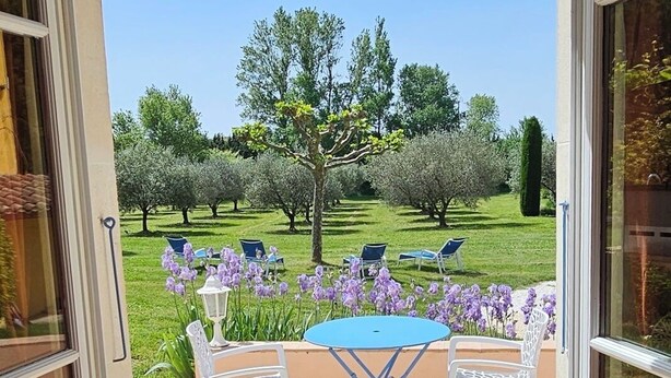 An open patio with a table and chairs, surrounded by a garden with trees and flowers. - Maison d'hôtes La Ramade, 5 chambres et table d'hôtes en Provence (12 pers) (Tulette)