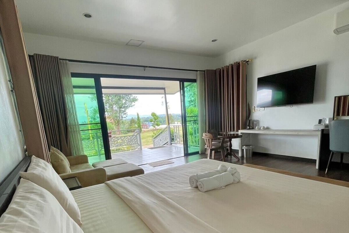 A hotel room with a large bed, a TV, a desk, and a view of the outdoors.