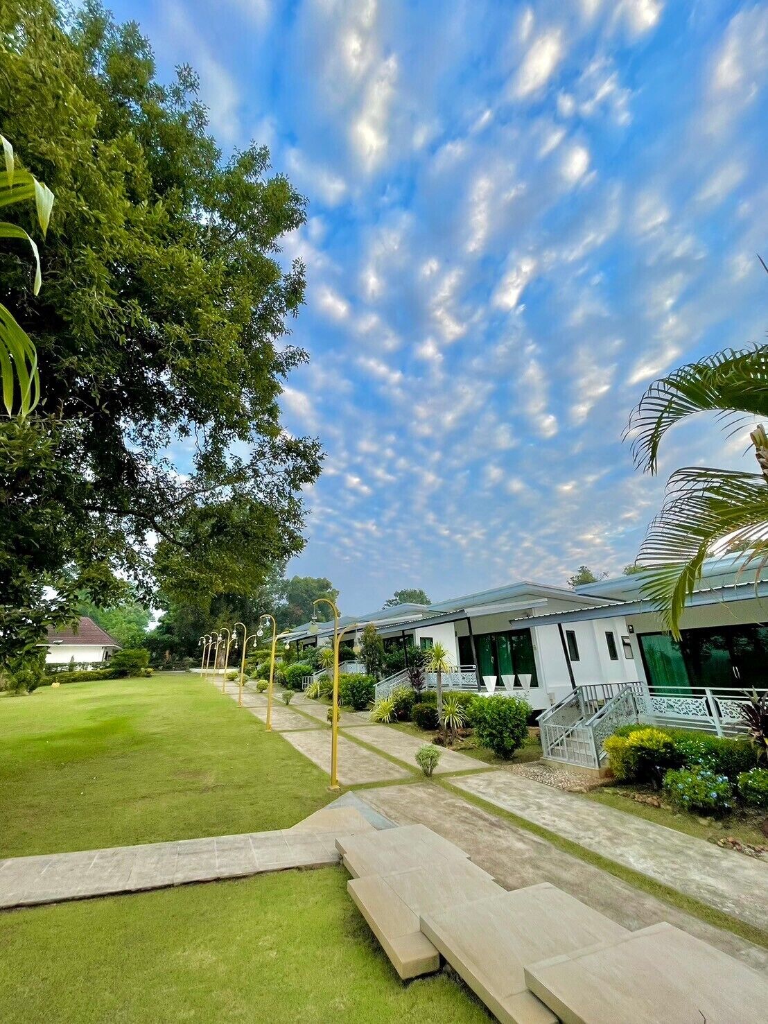 A hotel with a pathway leading to a building, surrounded by greenery and trees.