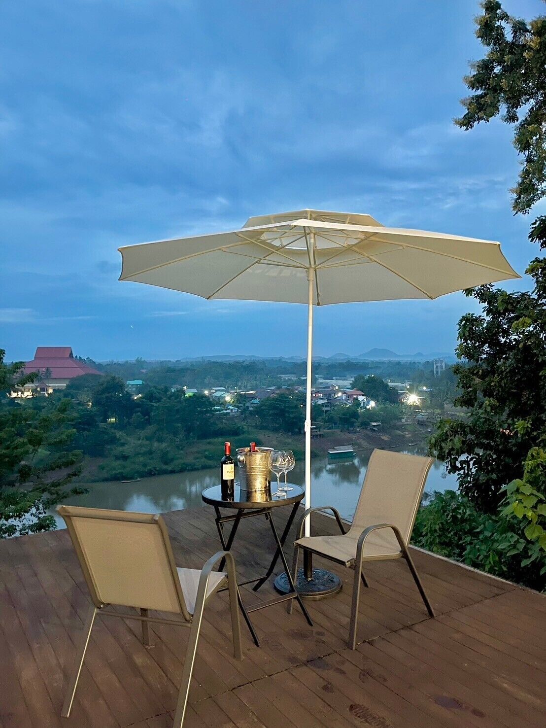 Una terraza con una mesa y sillas, una sombrilla, y vistas a un río y edificios al fondo.