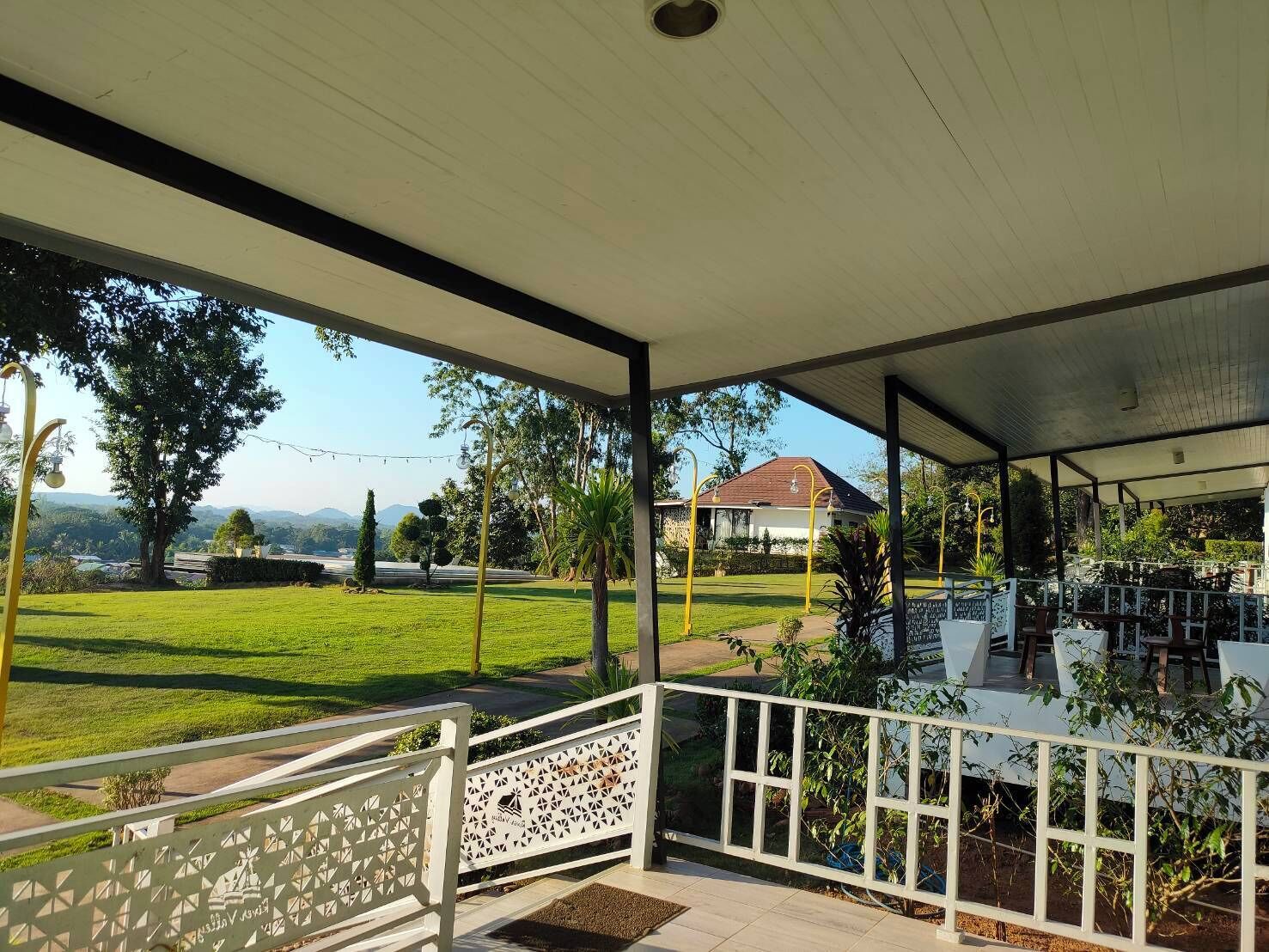 A covered outdoor area with a view of a house and a lawn.