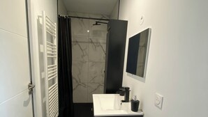 Ein modernes Badezimmer mit einem weißen Waschbecken, einem schwarzen Schrank und einer Dusche mit schwarzem Vorhang.
