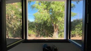 Ein Zimmer mit Fenster und Blick auf Bäume und Grün.