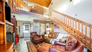 A spacious living room with leather furniture, a wooden staircase, and a stone floor. - Monroe Retreat with Mountain Views & Fire Pit! (Monroe)