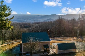 Une cabane avec un toit végétalisé, un sentier en pierre et une vue sur les montagnes lointaines.