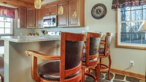 A kitchen with wooden cabinets, a stone floor, and a large island with bar stools. - Monroe Retreat with Mountain Views & Fire Pit! (Monroe)