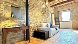Una habitación rústica con paredes de piedra vista, techo de madera, un sofá, una mesa y una chimenea.