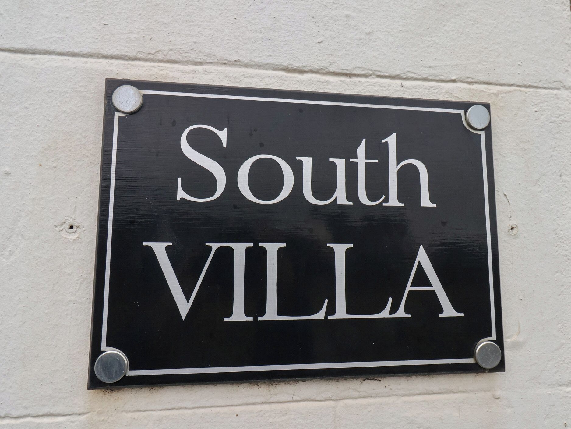 Un letrero negro con letras blancas que dice "South VILLA".