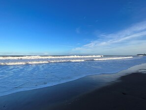 A beach with waves, a clear sky, and a distant shoreline. - South Villa (Whitby)