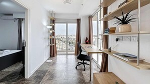 Ein modernes Apartment mit Balkon, Schreibtisch und Bücherregal.