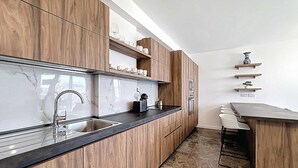 Eine moderne Küche mit Holzausstattung, Marmorspaltbrettern und einem eingebauten Ofen.