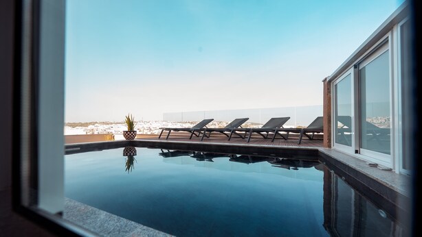 Ein Infinity-Pool auf dem Dach mit Liegestühlen und einem Blumentopf.