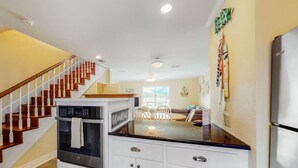 Una cocina con armarios blancos, un refrigerador de acero inoxidable y una escalera de madera.