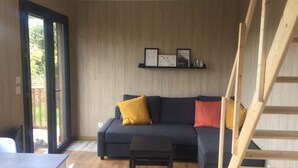 En moderne stue med en mørkegrå sofa, et lille sort bord og en trappe i træ.