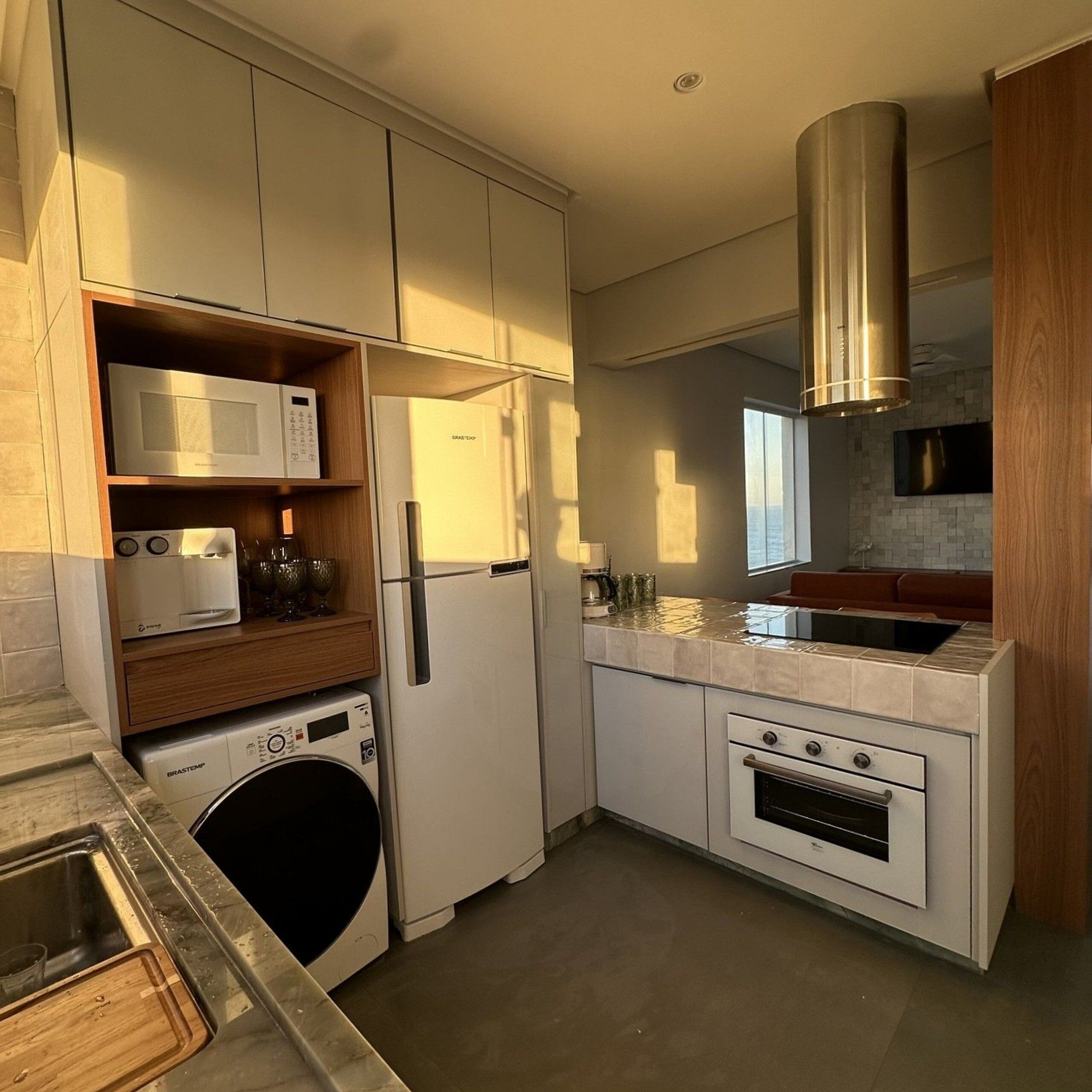 A compact kitchen with a microwave, refrigerator, oven, and washing machine.
