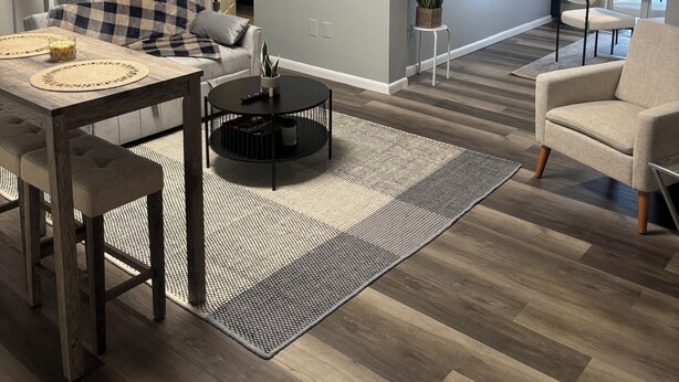 A modern living room with a dining area, a sofa, a coffee table, and a view of the adjacent room.