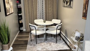A dining area with a round table and four chairs, a ceiling fan, and a potted plant.