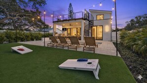 Uma casa moderna com um pátio, área de estar externa e luzes de cordão.