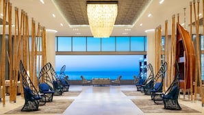 Un espace de détente moderne avec vue sur l’océan, agrémenté de cloisons en bambou et de fauteuils suspendus.