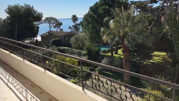 A balcony with a view of a landscaped garden, a pool, and the sea. - Villa Cap d’Antibes - See view (Antibes)