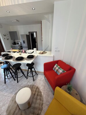Eine moderne Küche mit Essbereich, ausgestattet mit einem roten Sofa, einem gelben Sessel und einem kleinen Topfpflanzen.
