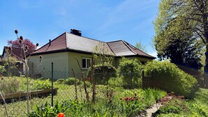 A house with a tiled roof, surrounded by a garden with various plants and flowers.
