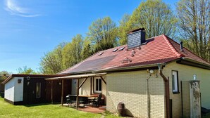 A single-story house with a red-tiled roof, a brick exterior, and a small attached garage.