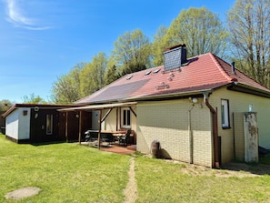 A single-story house with a red-tiled roof, a brick exterior, and a small attached garage. - Vacation home directly on the lake 50m to the beach with garden and fireplace (Warin)