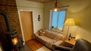 A cozy living room with a fireplace, a sofa, a leather chair, and a window with blinds.