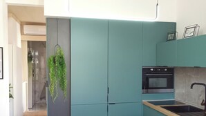 Una cocina moderna con armarios color turquesa, encimera de madera y horno negro.