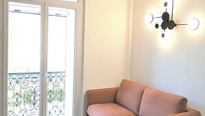 Una sala de estar moderna con un sofá, una mesa redonda y un aplique de pared.
