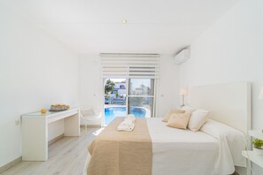 A modern hotel room with a bed, desk, and a view of a swimming pool. - 0149-VALIRA House at the canal with pool and mooring (Empuriabrava)