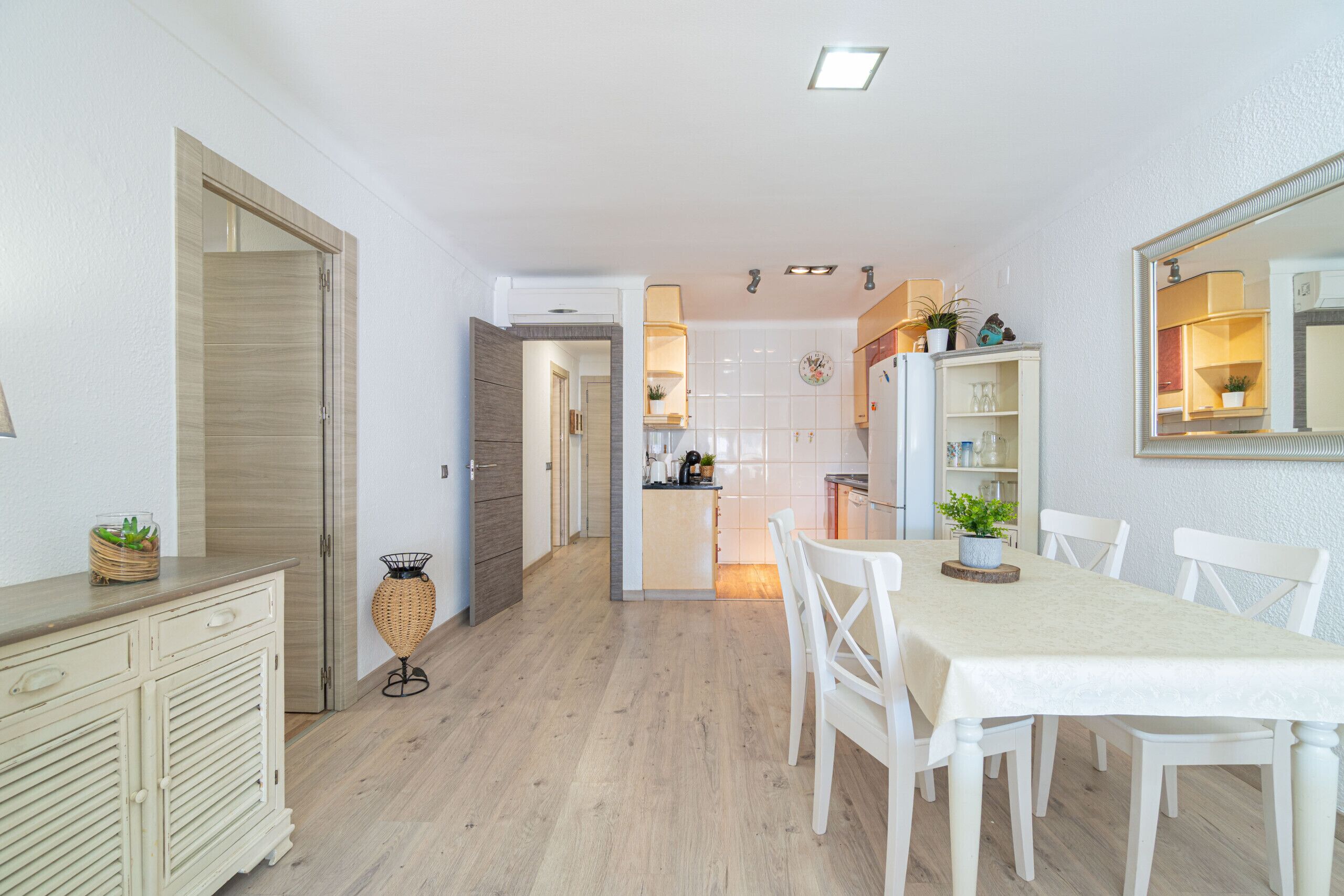 Une cuisine moderne avec un coin repas, des meubles en bois et une table blanche.