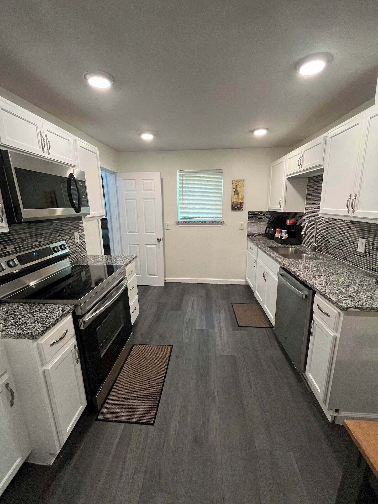 A modern kitchen with white cabinetry, stainless steel appliances, and a gray floor.