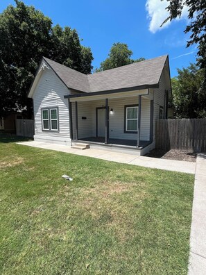 A single-story house with a front porch, a fenced yard, and a clear sky. - Econo Comfort near TCU & Downtown (Fort Worth)