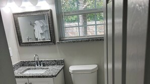 Een badkamer met toilet, wastafel en spiegel.