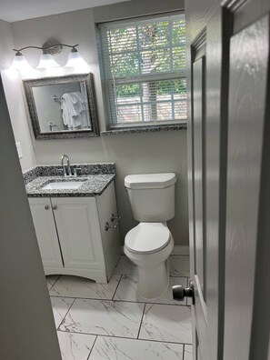 A bathroom with a toilet, sink, and mirror. - Econo Comfort near TCU & Downtown (Fort Worth)