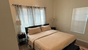 Een slaapkamer met een bed, nachtkastjes, een plafondventilator en een raam met zonwering.