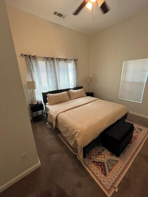 A bedroom with a bed, bedside tables, a ceiling fan, and a window with blinds. - Econo Comfort near TCU & Downtown (Fort Worth)